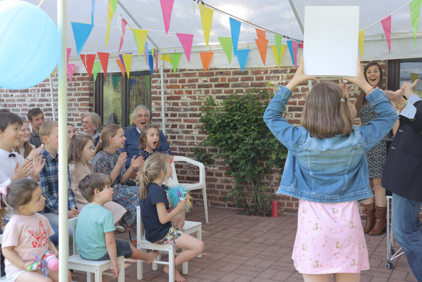 Des enfants amusés réagissent avec des applaudissements enthousiastes aux tours du magicien pour enfants Tony Price.