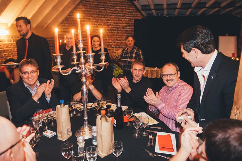 People at the table applaud close-up magician Tony Price after a magic trick.