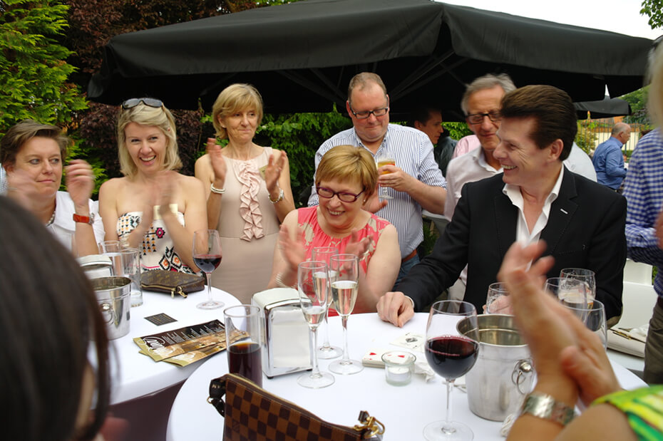 Spectators applaud magician Tony Price after a successful trick.