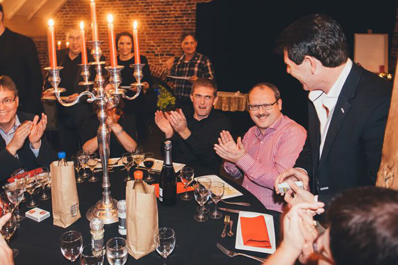 At the table people applaud for Tony's (card) tricks.