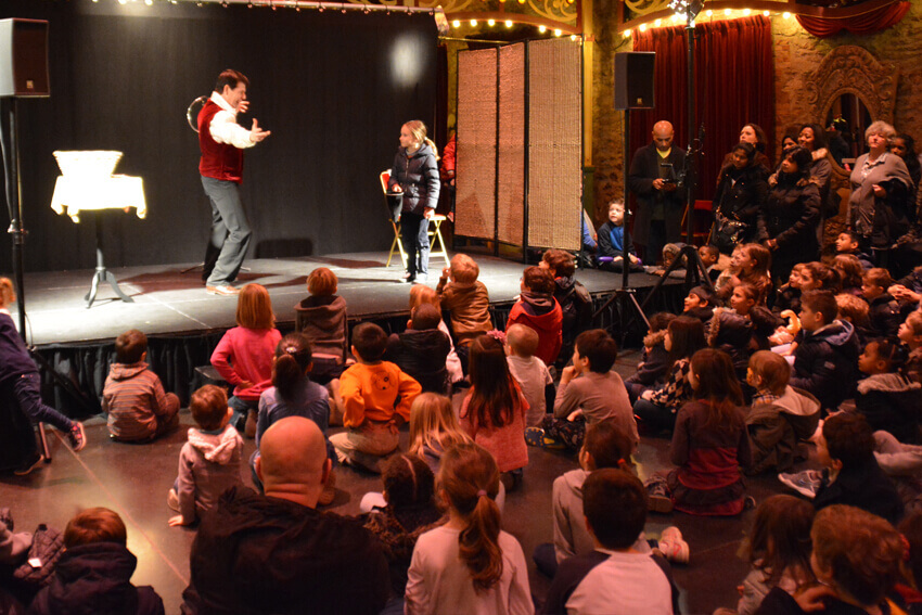 Children watch animatedly and amusedly at children's magician Tony Price.